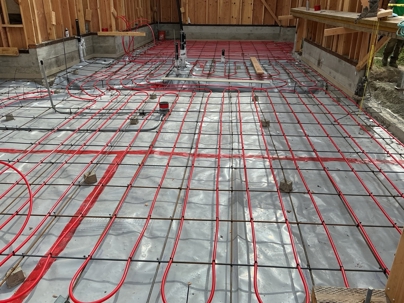 Hydronic PEX tubing laid over rebar and vapor barrier before concrete pour — radiant floor heating installation by Nigel Mulgrew Plumbing, San Francisco